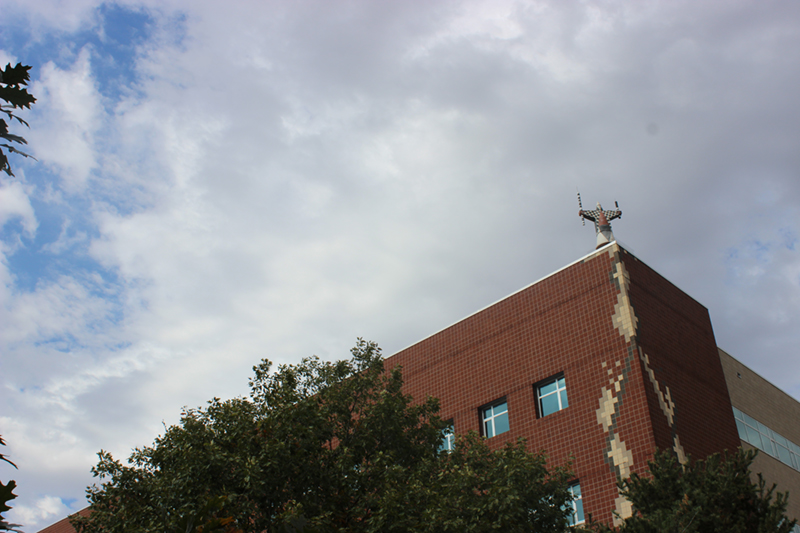 Photo of Molecular Biology building from ground with sky in background. A metal sculpture is on the roof corner.
