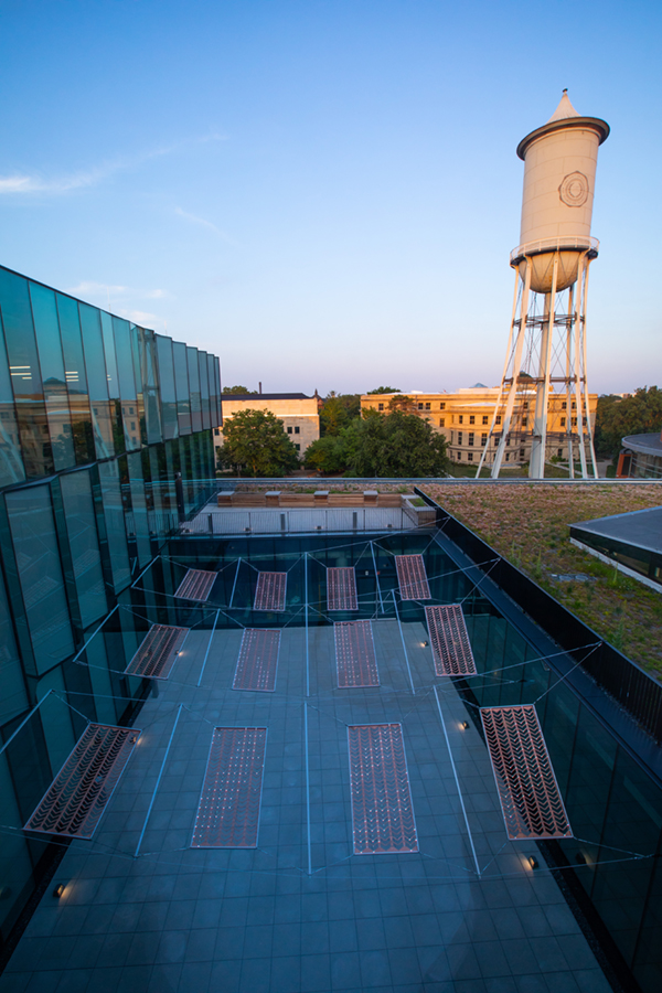 Photo looking down on a courtyard with suspended copper panels. The Marston water tower is in the background.